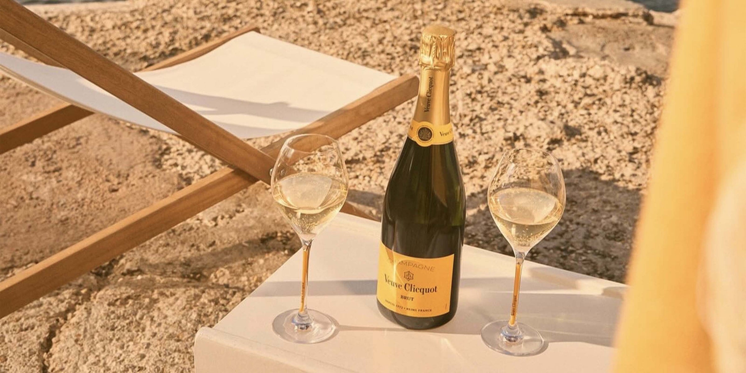 Veuve Clicquot Brut champagneflaske og to glas på en strandstol