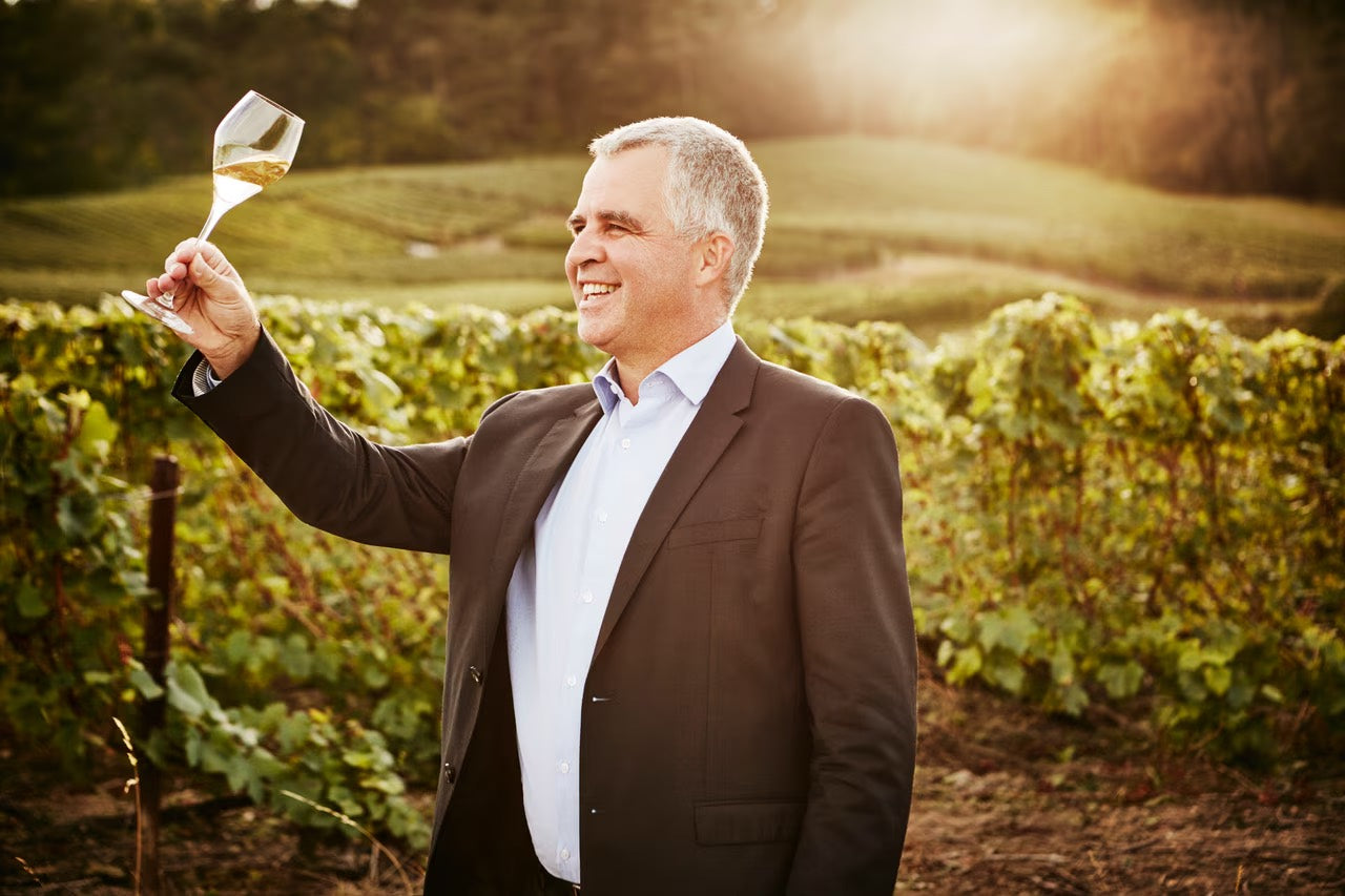 Olivier Krug inspicerer vin markerne med et glas champagne i solnedgang