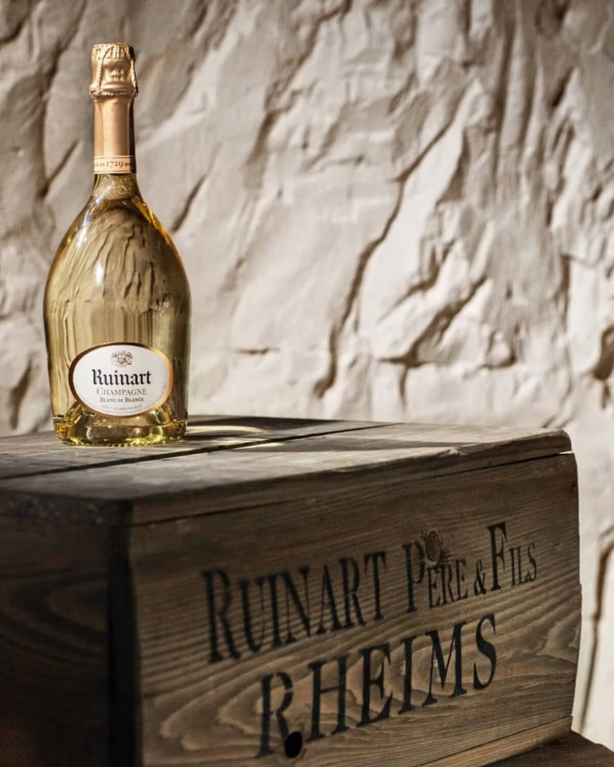 Ruinart champagneflaske i historiske kridtkældre i Reims
