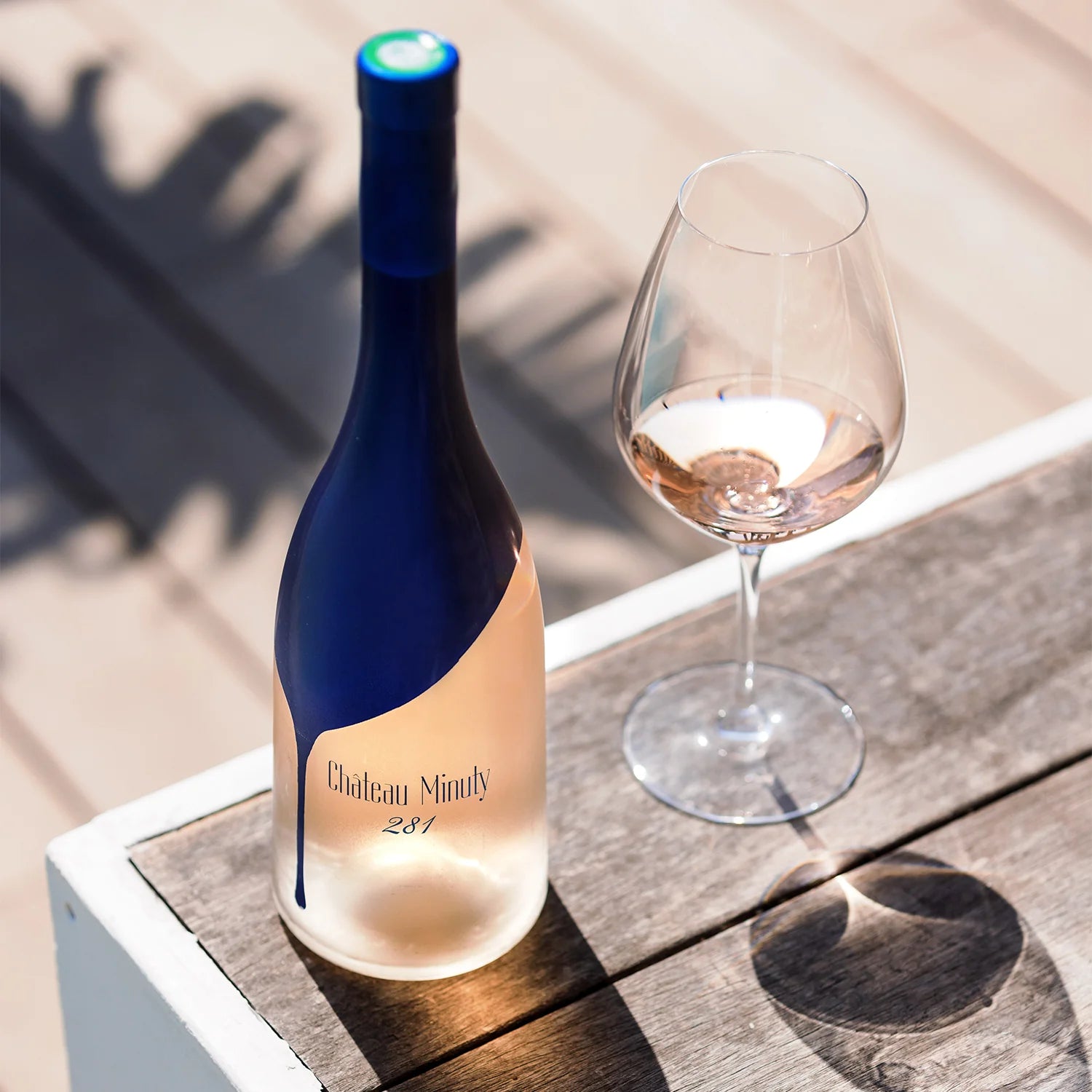 Chateau Minuty 281 rosévin flaske og glas på et træbord i solen