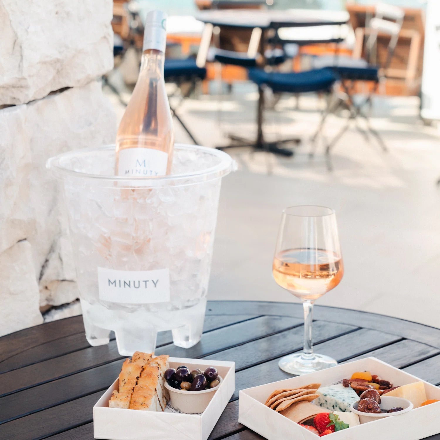 Minuty rosévin i spand med is, glas vin og charcuteri på bord