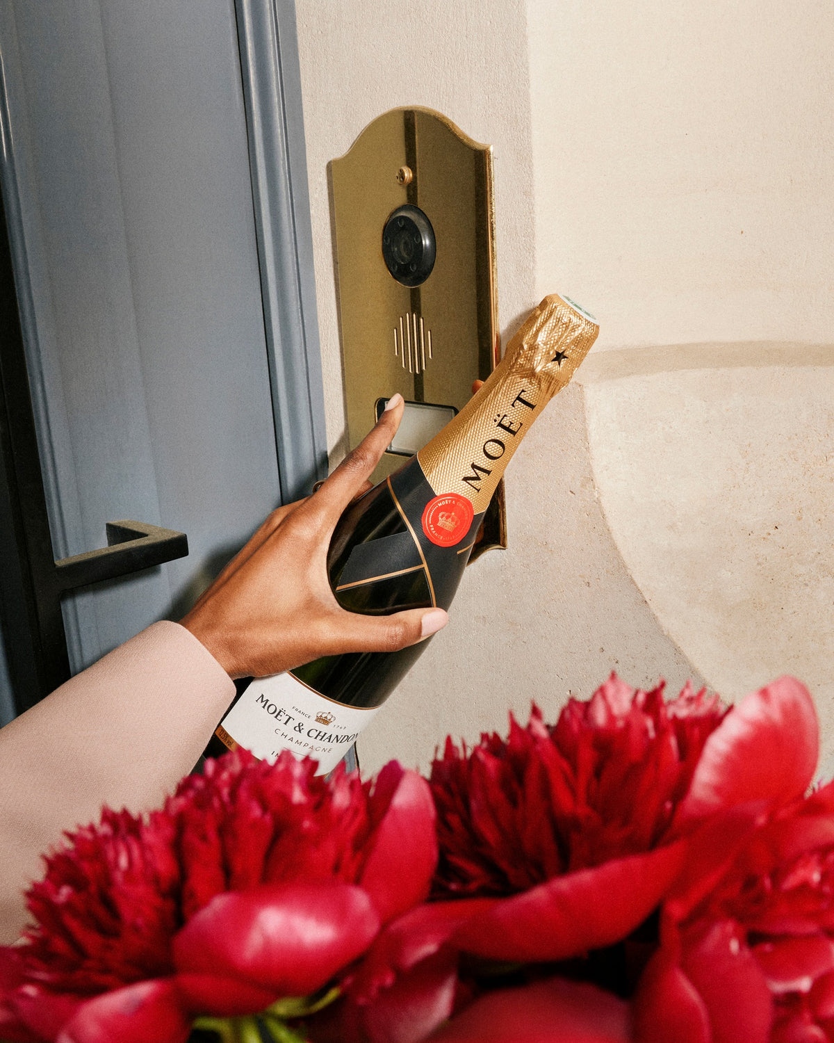 En flaske Moet Brut Imperial og en flot rød buket blomster.