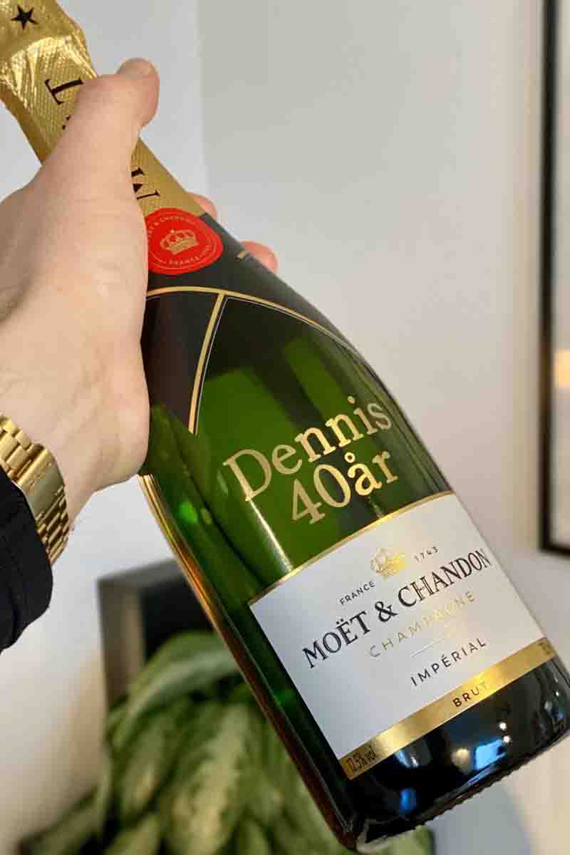 Manden holder Moët & Chandon med personliggjort guldskrift "Dennis 40 år"