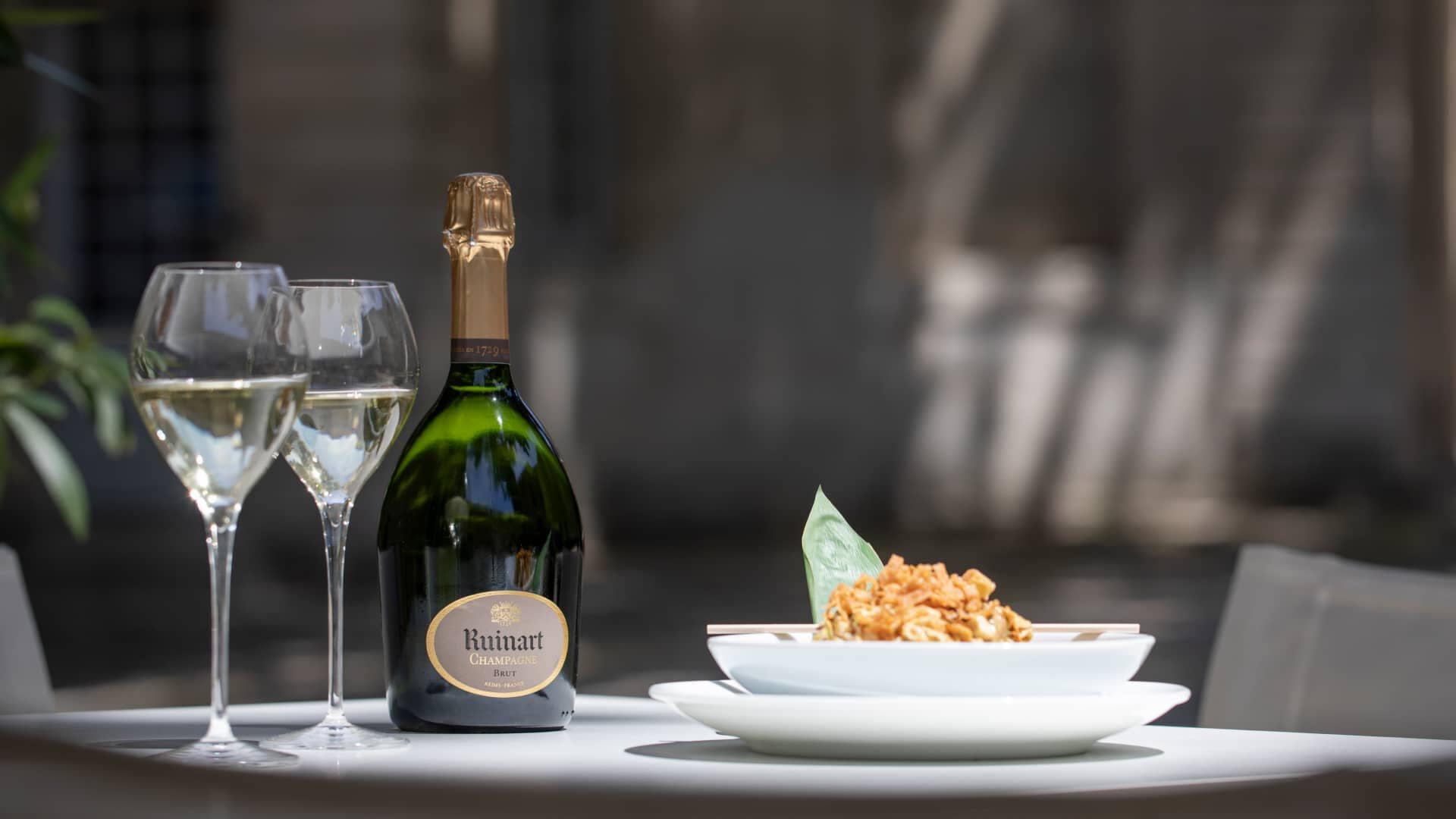 Ruinart R de Ruinart Brut champagne med to glas og mad på bord