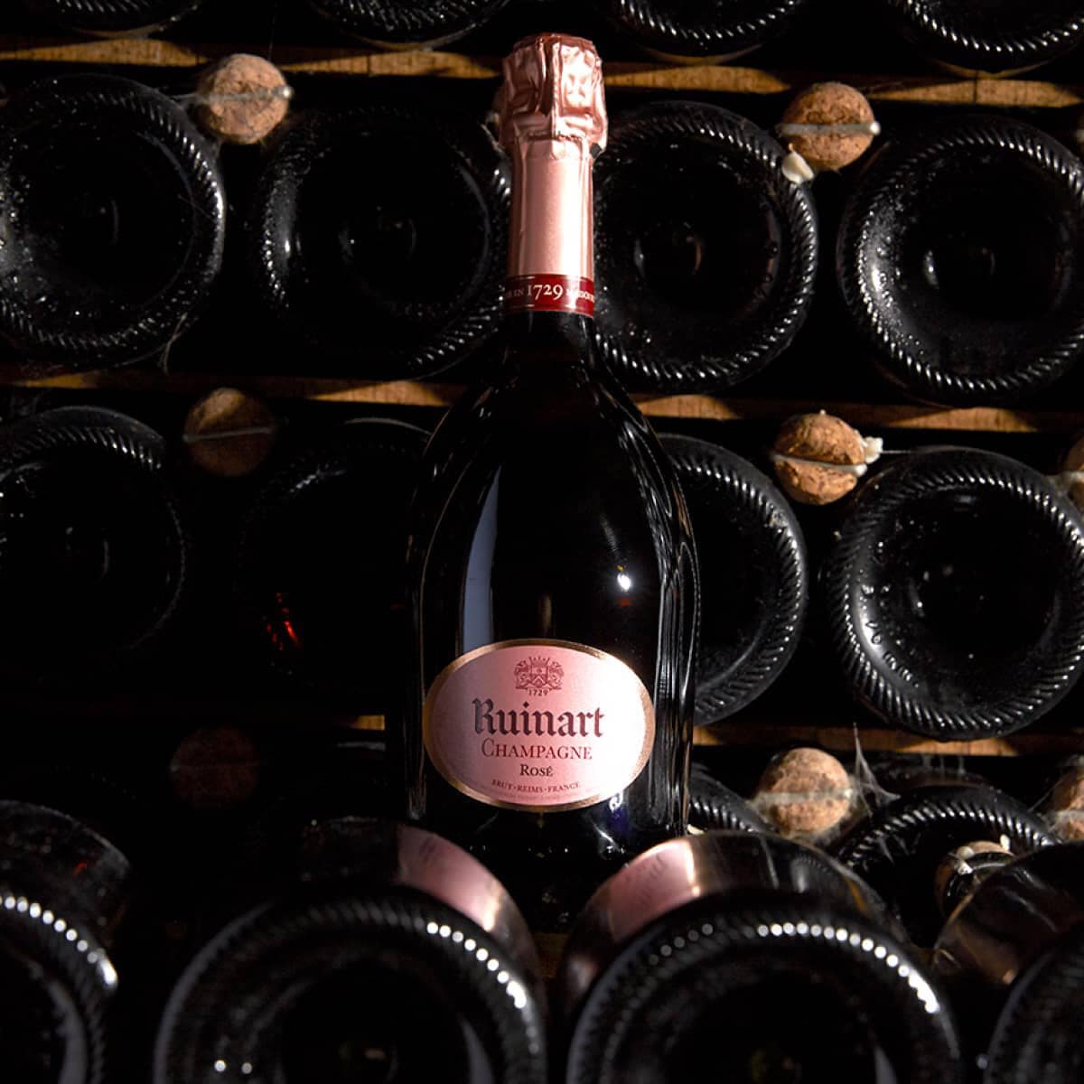 Ruinart champagne rosé flaske i et mørkt kældermiljø