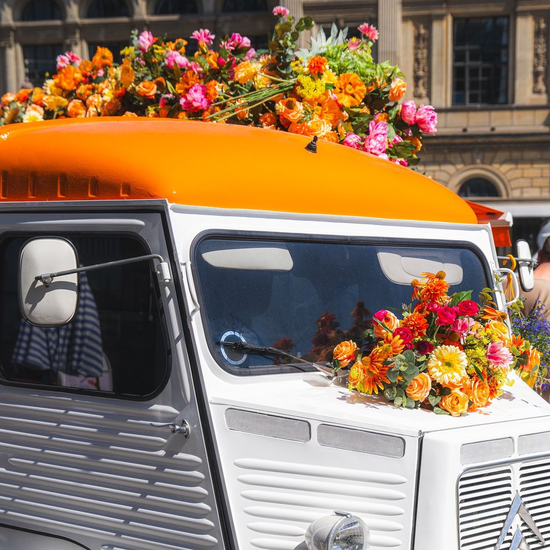 Hvid varevogn med orange tag dekoreret med farverige blomsterbuketter.