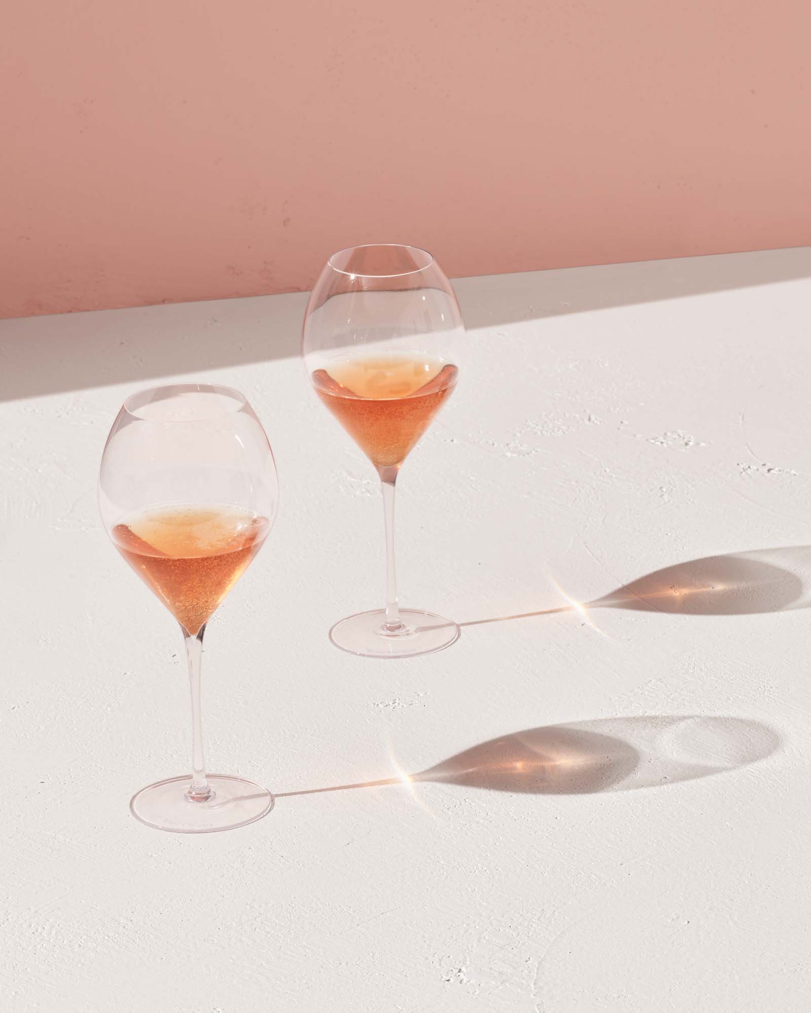 To glas rosé champagne på et hvidt bord med lyserød baggrund
