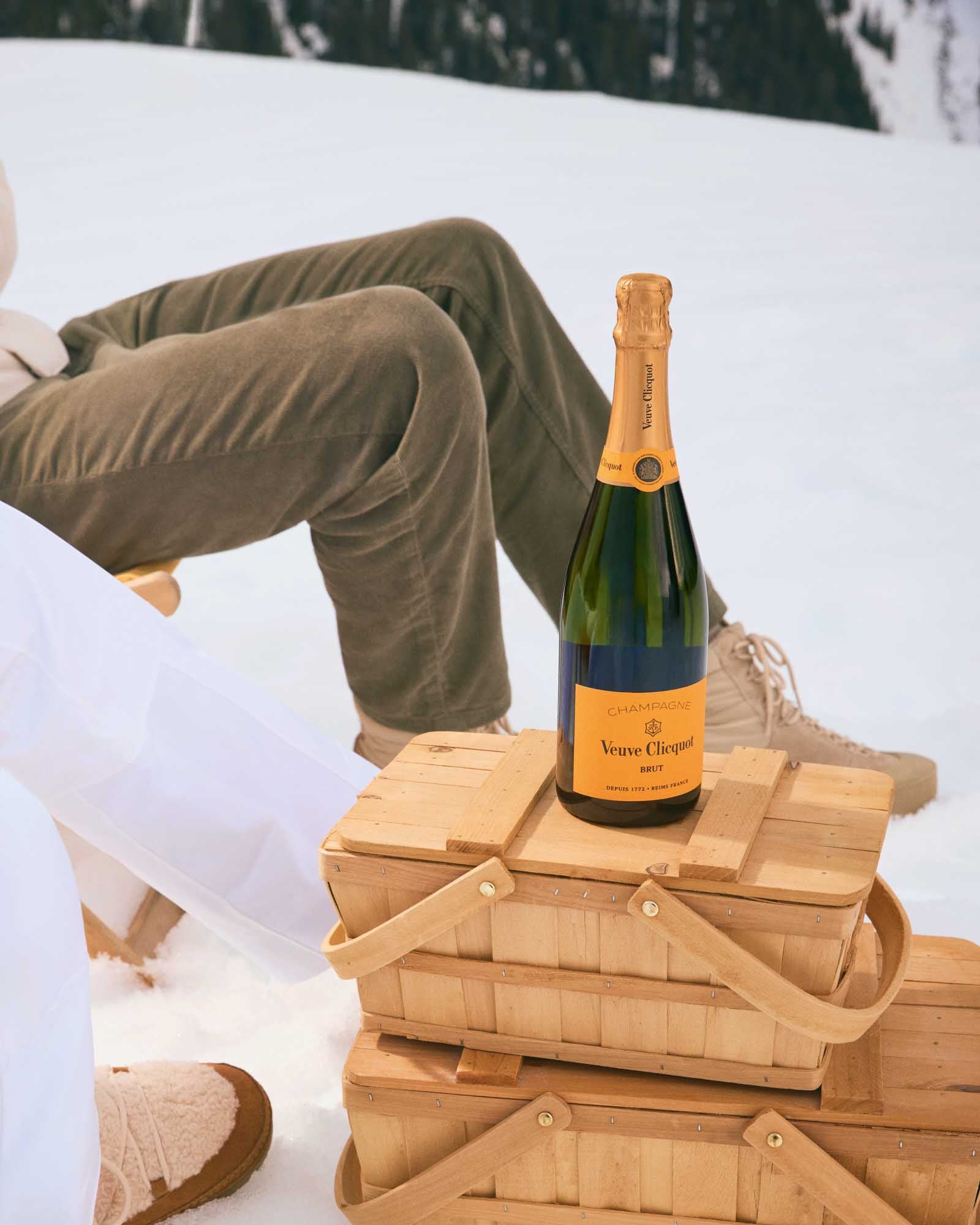 Veuve Clicquot Champagne flaske stående på picnickurve i snefulde omgivelser