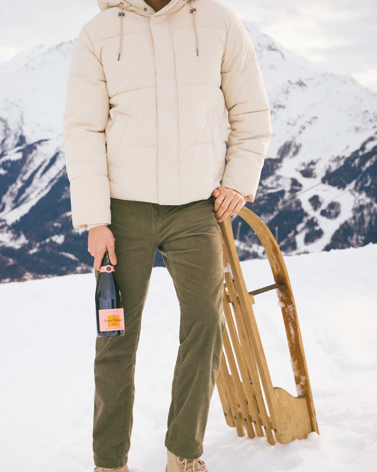 Person med Veuve Clicquot Rose champagne og kælk i sneen.