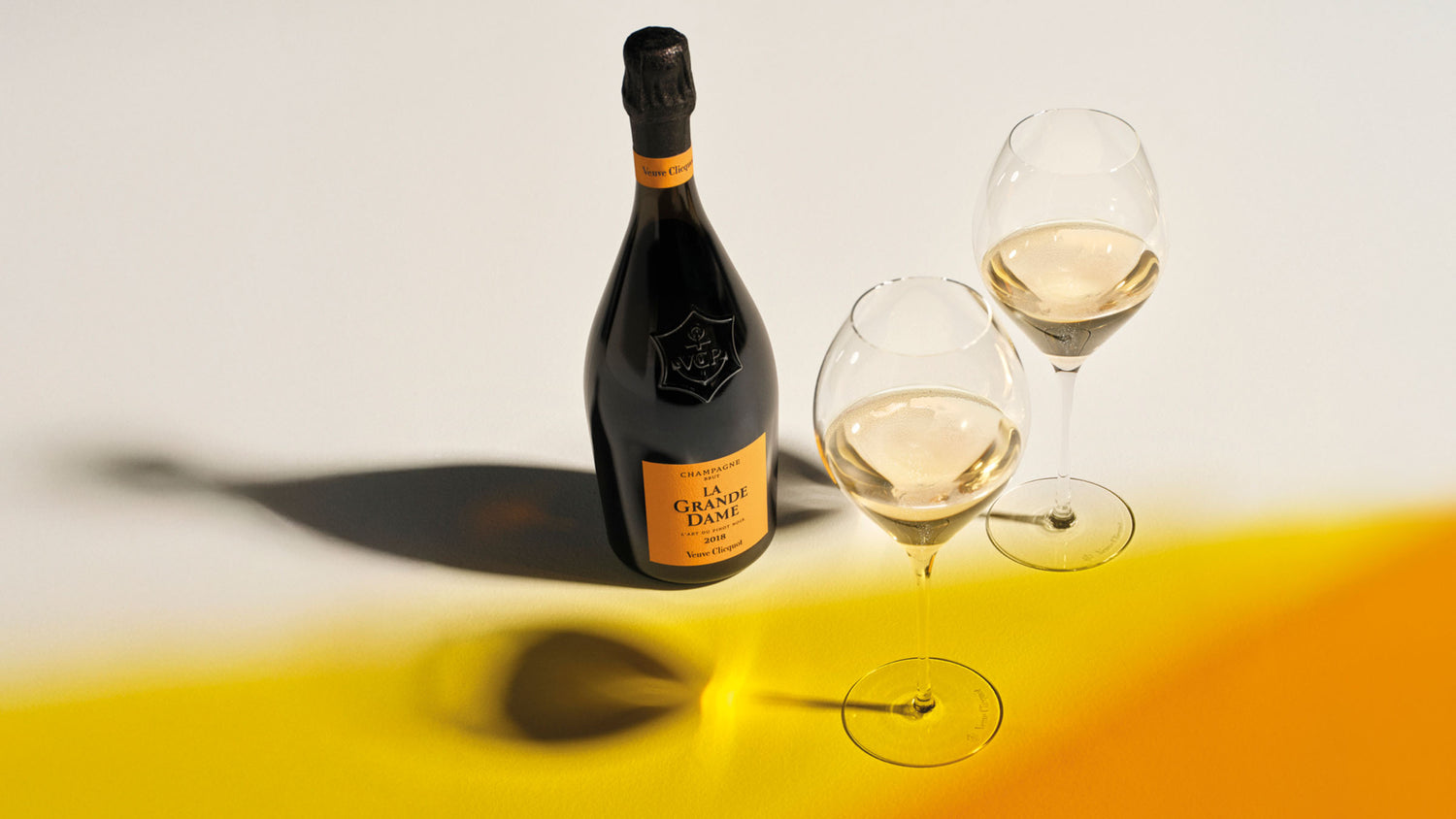 Veuve Clicquot La Grande Dame 2018 champagneflaske med to glas på gul baggrund