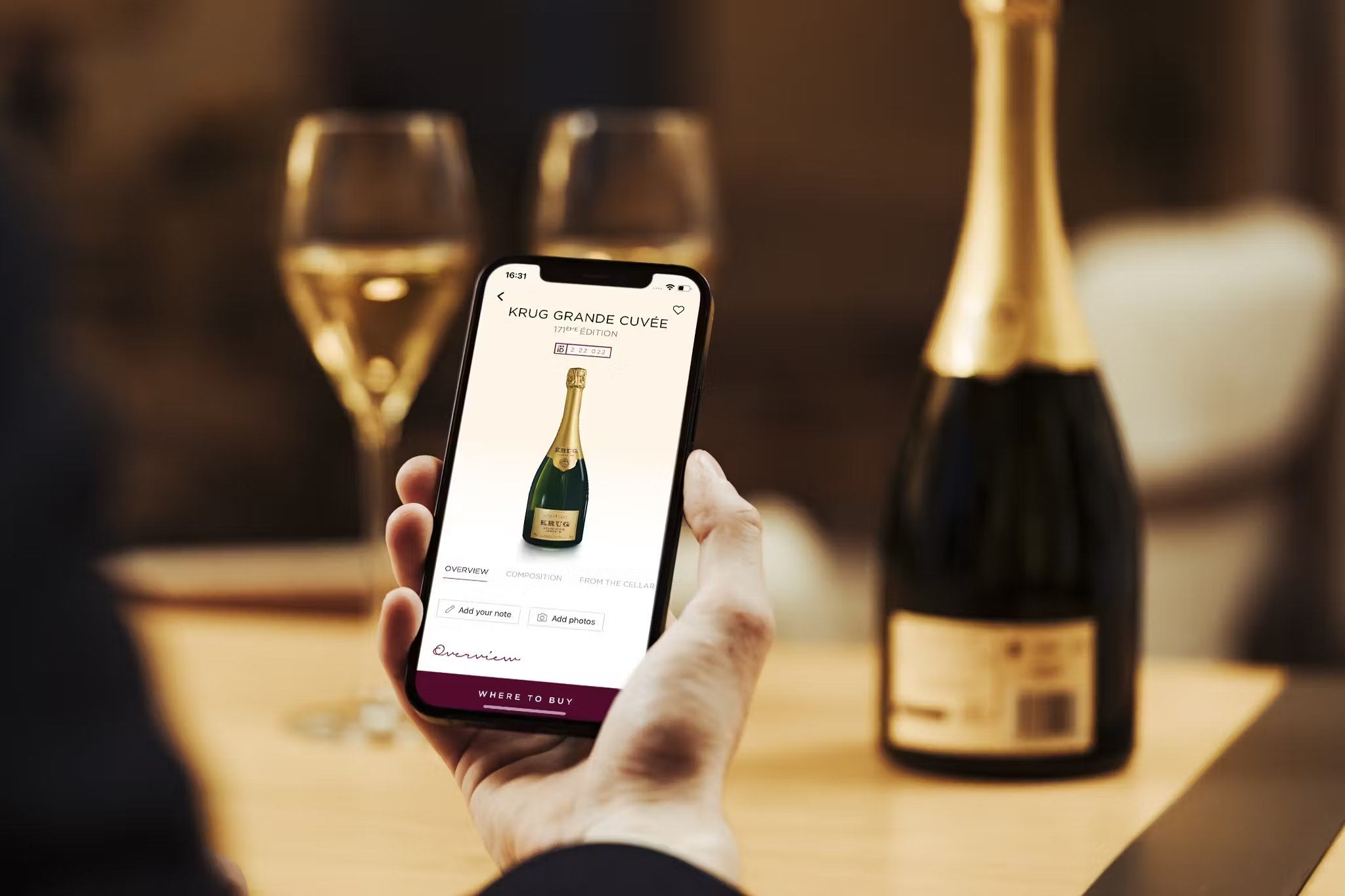 Mand holder mobil med Krug app, digital flaske Krug Grande Cuvée og champagneglas.