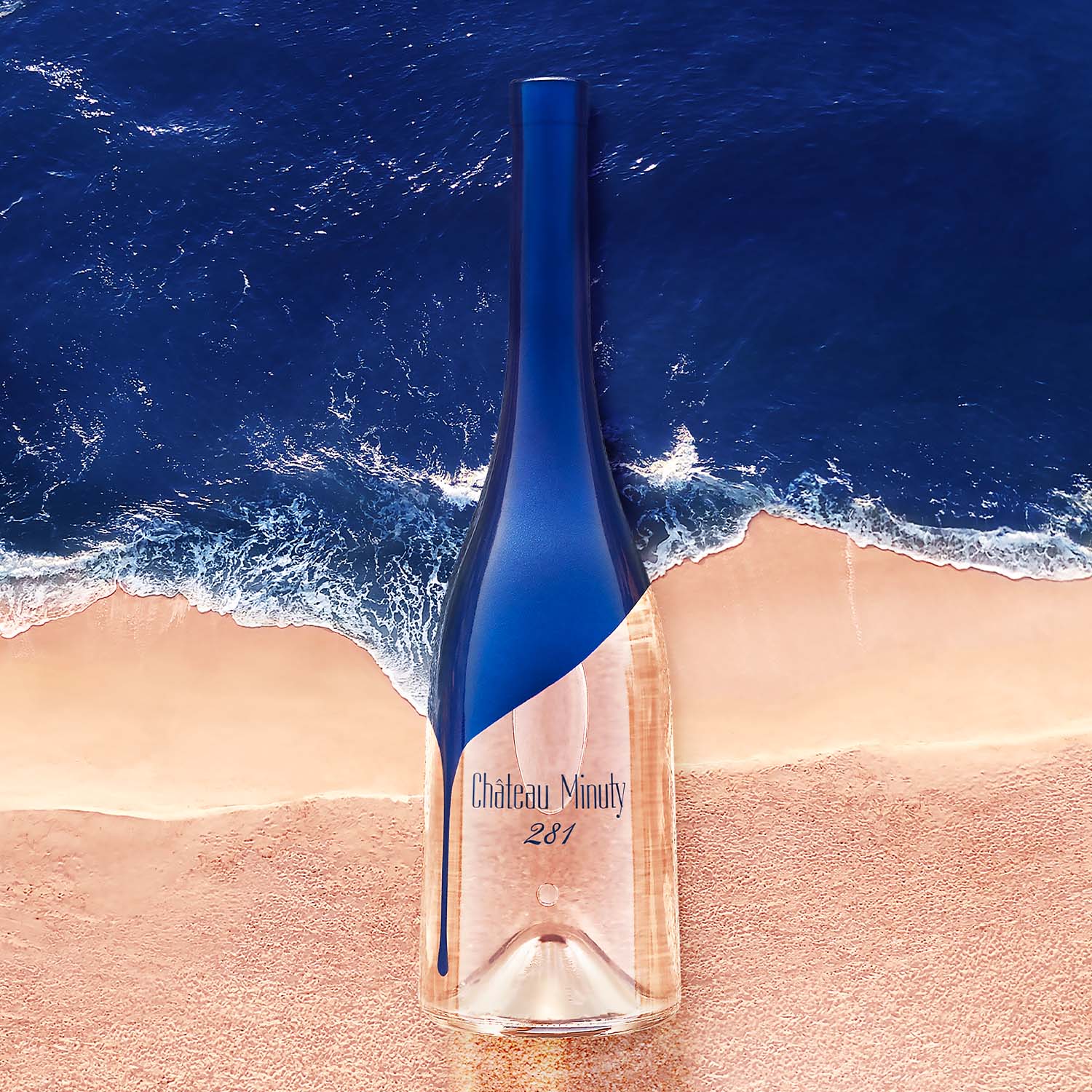 Chateau Minuty 281 rosévin flaske på strand med havbølger